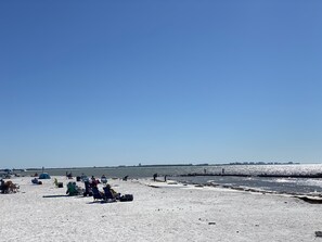 Una playa con gente relajándose en sillas y tomando el sol.