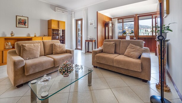 Una sala de estar con dos sofás beige, una mesa de centro de vidrio y un aparador de madera.