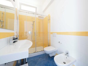 A modern bathroom with a glass shower enclosure, a white sink, a toilet, and a bidet. - Mayor House (Sorrento)