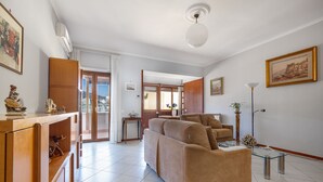 Amplia sala de estar con sofá, un mueble de madera y un ventilador de techo.
