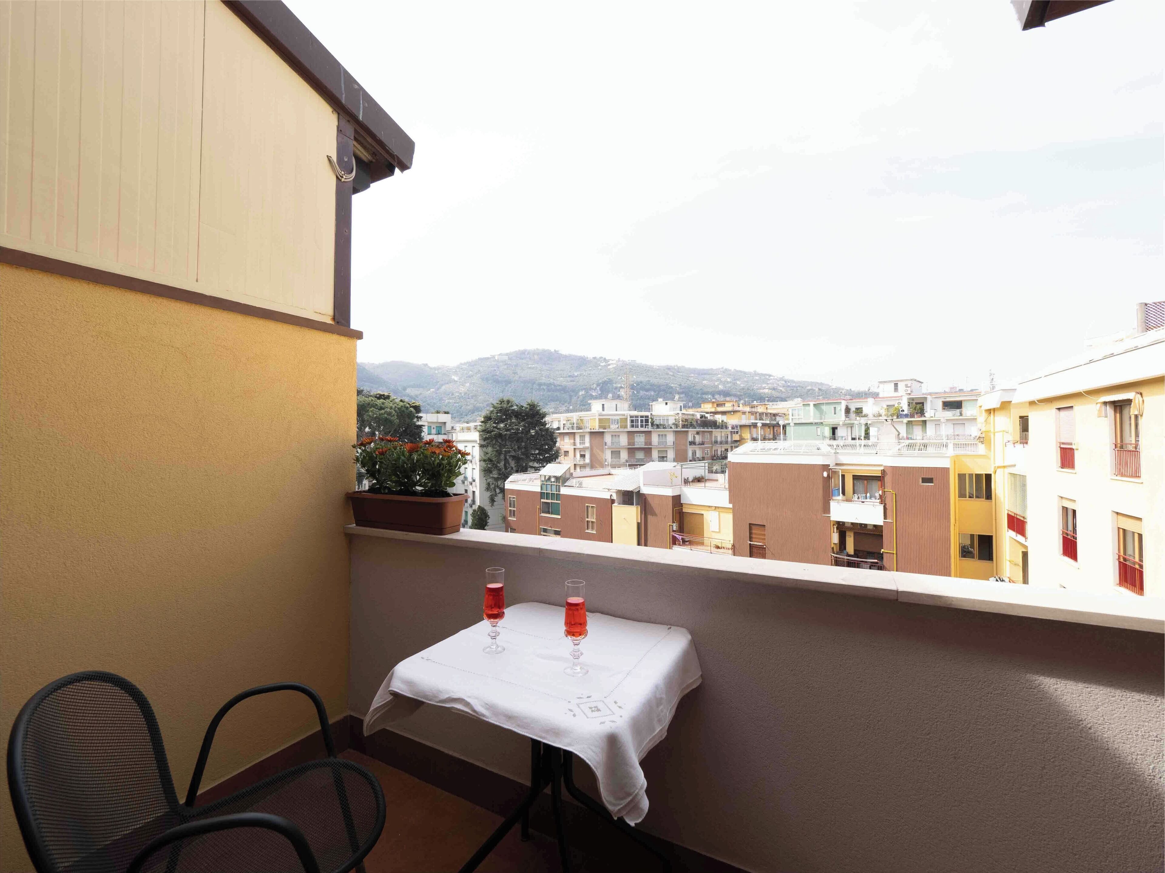 A balcony with a table, two chairs, and a potted plant.