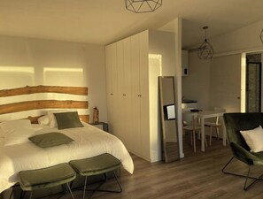 Relax in a stylish room with a large bed, wooden headboard, and a dining area with a table and chairs.
