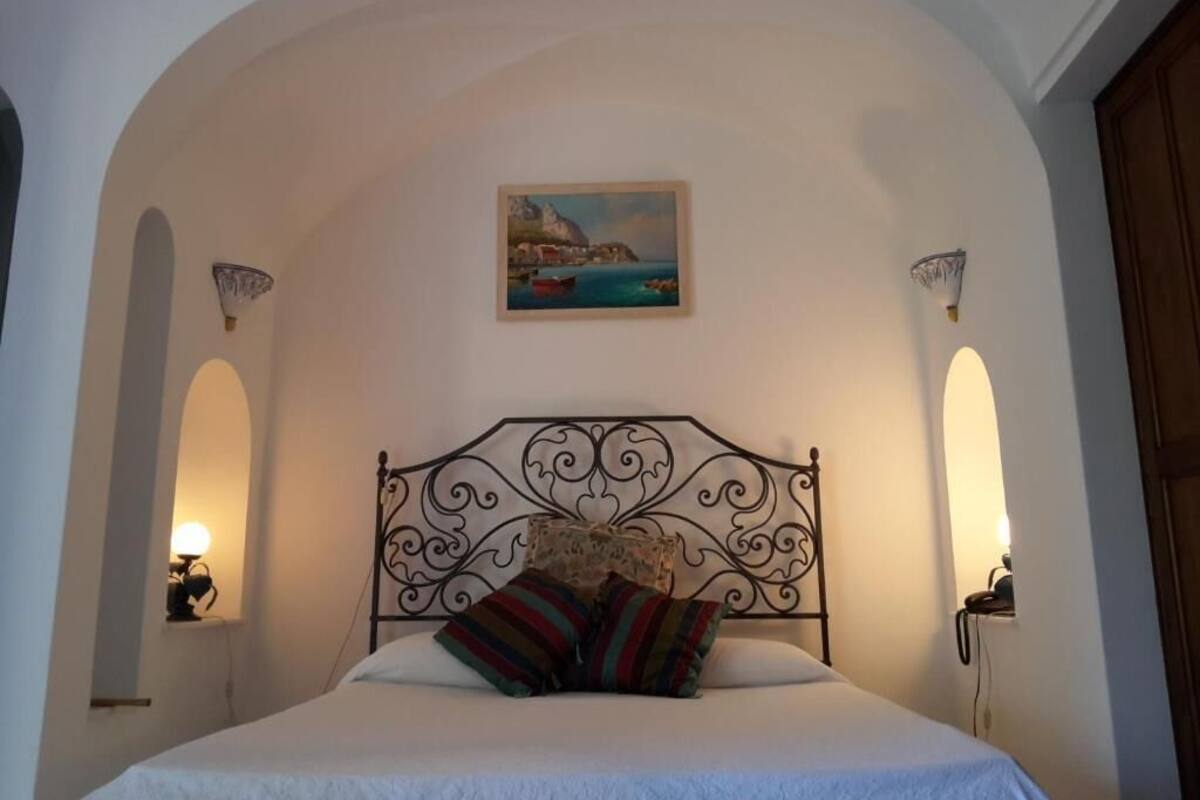 Une chambre à coucher avec un lit, un tableau et deux appliques murales.