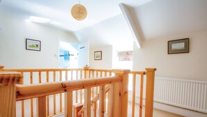 A wooden staircase with a handrail, white walls, and framed pictures on the walls. - Berry Hall - Porty Eynon (Swansea)