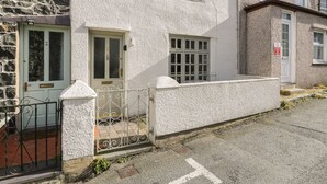 Une maison à deux étages avec une façade en pierre, une couleur blanche et un portail en métal.