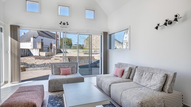 A spacious living room with a large sofa, a coffee table, and a view through large glass doors to an outdoor area. - Large house for 8 people in St Armel (Saint-Armel)