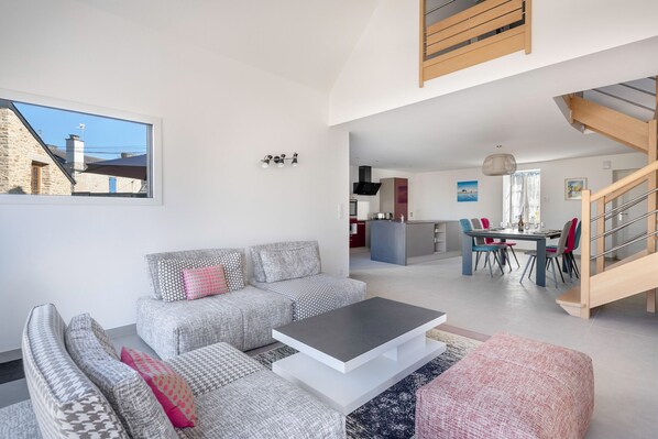 Amplia sala de estar con un conjunto de sofás, una mesa de centro y vistas al área de cocina y comedor.