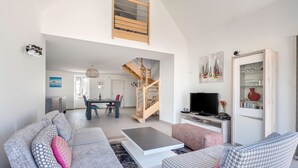 A spacious living area with a modern staircase, a flat-screen TV, and a dining area. - Large house for 8 people in St Armel (Saint-Armel)
