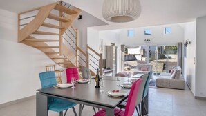A modern dining area with a wooden staircase, a dining table set with plates and glasses, and a large pendant light. - Large house for 8 people in St Armel (Saint-Armel)