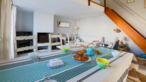 A dining area with a table set for breakfast, including croissants and a green bowl. - Cosy family house for 6 in Les Portes en Ré (Les Portes-en-Ré)