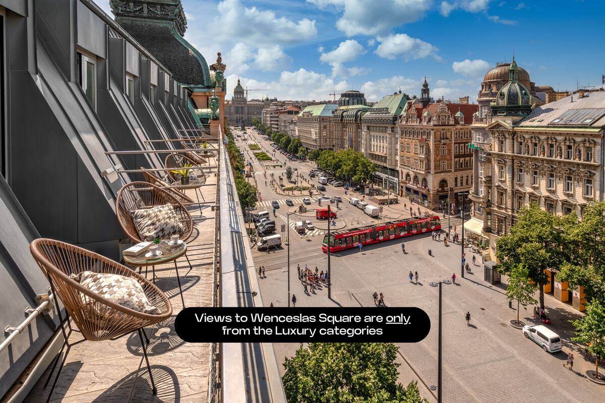 Vista de uma varanda sobre uma praça urbana com edifícios históricos, um elétrico vermelho e céu limpo.