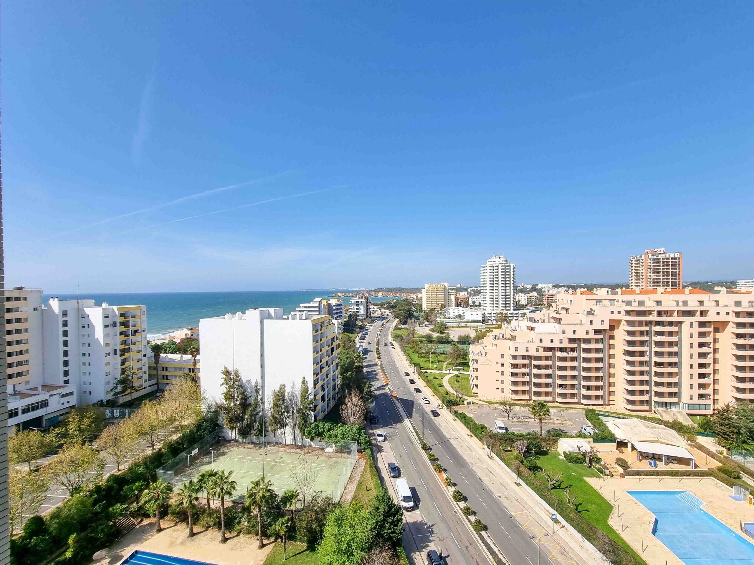 Un quartier résidentiel avec de grands immeubles, une route et une plage en arrière-plan.