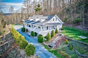 A two-story house with a porch, surrounded by a well-maintained lawn and trees.
