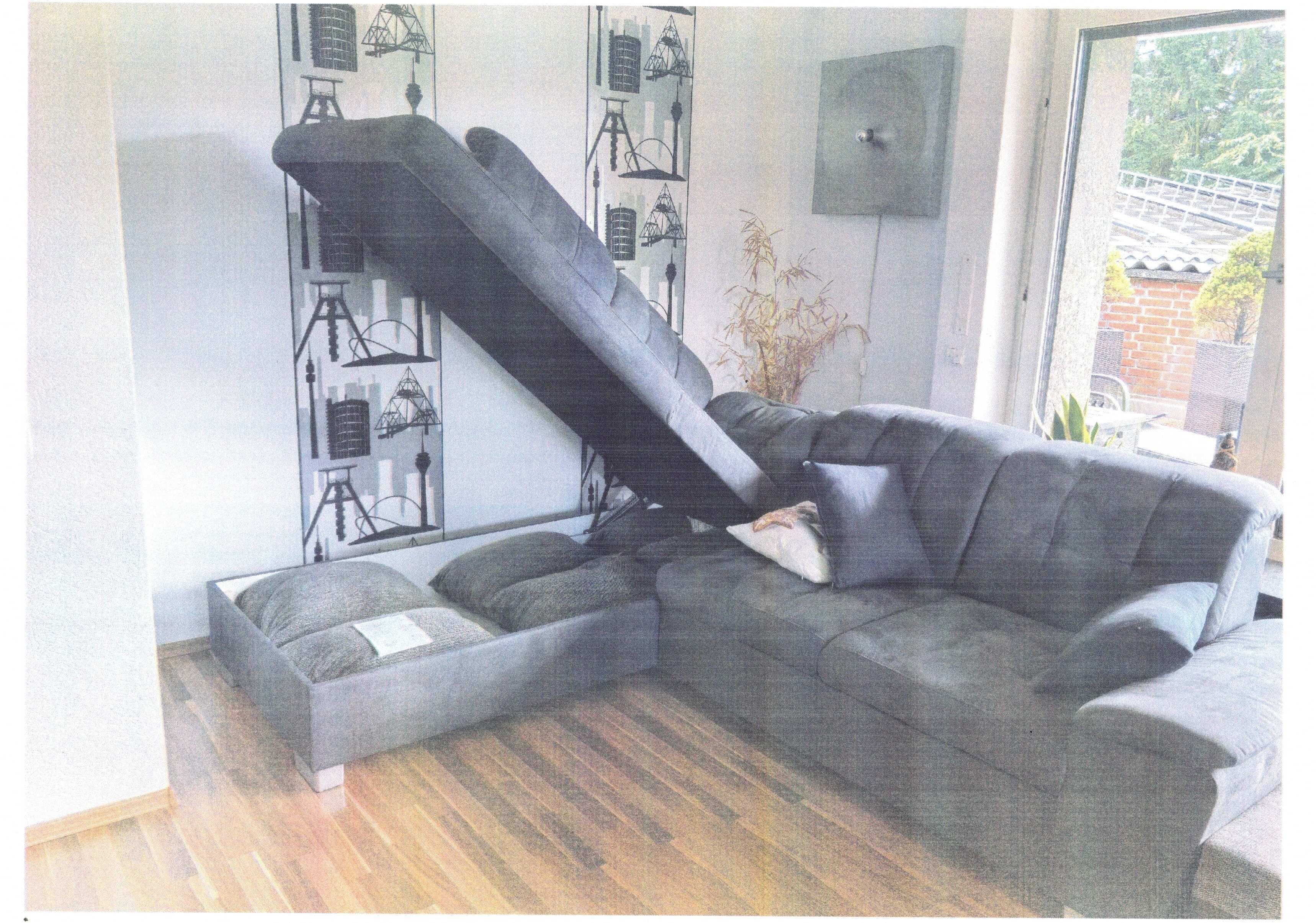A modern living room with a sectional sofa, a small table, and a decorative wall with abstract designs.