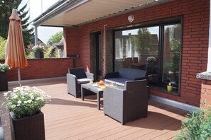 En terrasse med fletningsmøbler, et bord med frugt og krukkeplanter.