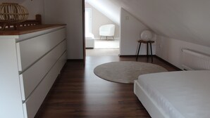 A bedroom with a wooden dresser, a round rug, a bed, a chair, and a radiator. - Cottage in Kluess (Güstrow OT KLueß)