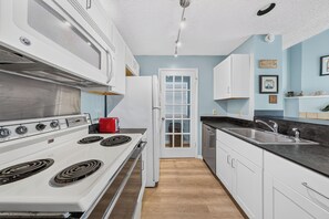 A kitchen with white cabinets, a stove, and a red toaster.