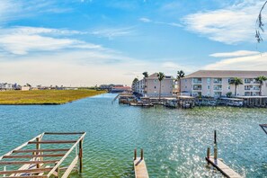 A waterfront property with a dock, a marina, and a row of buildings with balconies. - Canal-Front Escape | Pool, Hot Tub & Water Views (Corpus Christi)