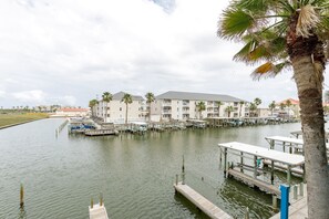 A marina with docked boats, a wooden dock, and a building with balconies.