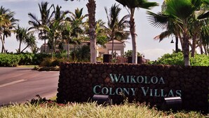 Skilt for Waikoloa Colony Villas med en stenvæg og palmer i baggrunden.