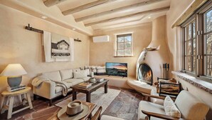 A cozy living room with a fireplace, a sofa set, a coffee table, and a rustic stone floor. - Luxurious Renovated Pueblo Style Home (Santa Fe)