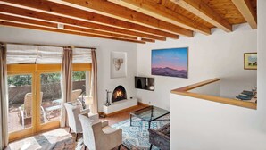 A cozy living room with a fireplace, a glass coffee table, and a view of the outdoors. - Amazing Mountain Views, Communal Pool (Santa Fe)
