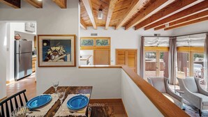 A modern kitchen with wooden beams, a dining area with blue plates, and a view of the outdoors. - Amazing Mountain Views, Communal Pool (Santa Fe)