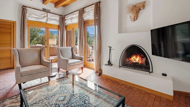 A modern living room with a fireplace, comfortable seating, and a large window offering a scenic view. - Amazing Mountain Views, Communal Pool (Santa Fe)