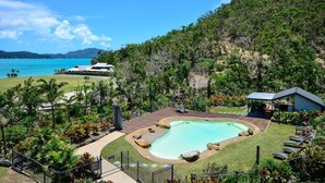 A resort with a swimming pool, lounge chairs, and a view of the ocean. - Frangipani Lodge F7, Frangipani Lodge F7 (Hamilton Island)