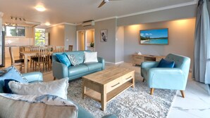 A spacious living area with a dining table, two sofas, and a coffee table. - Frangipani Lodge F7, Frangipani Lodge F7 (Hamilton Island)