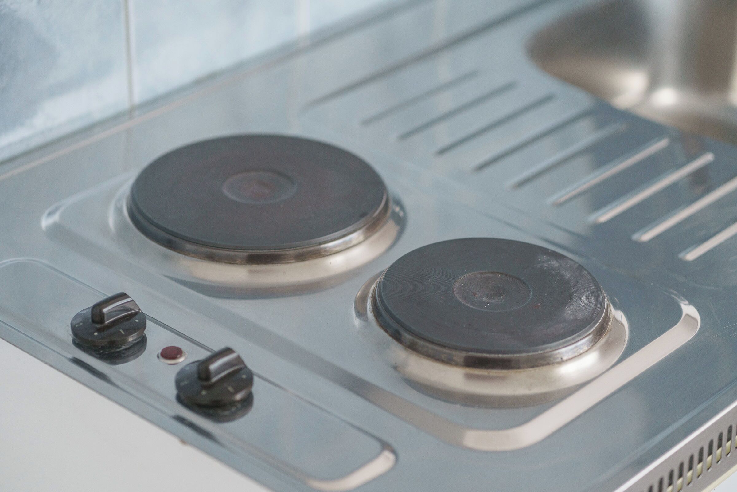 A kitchen with two stovetops and three knobs.