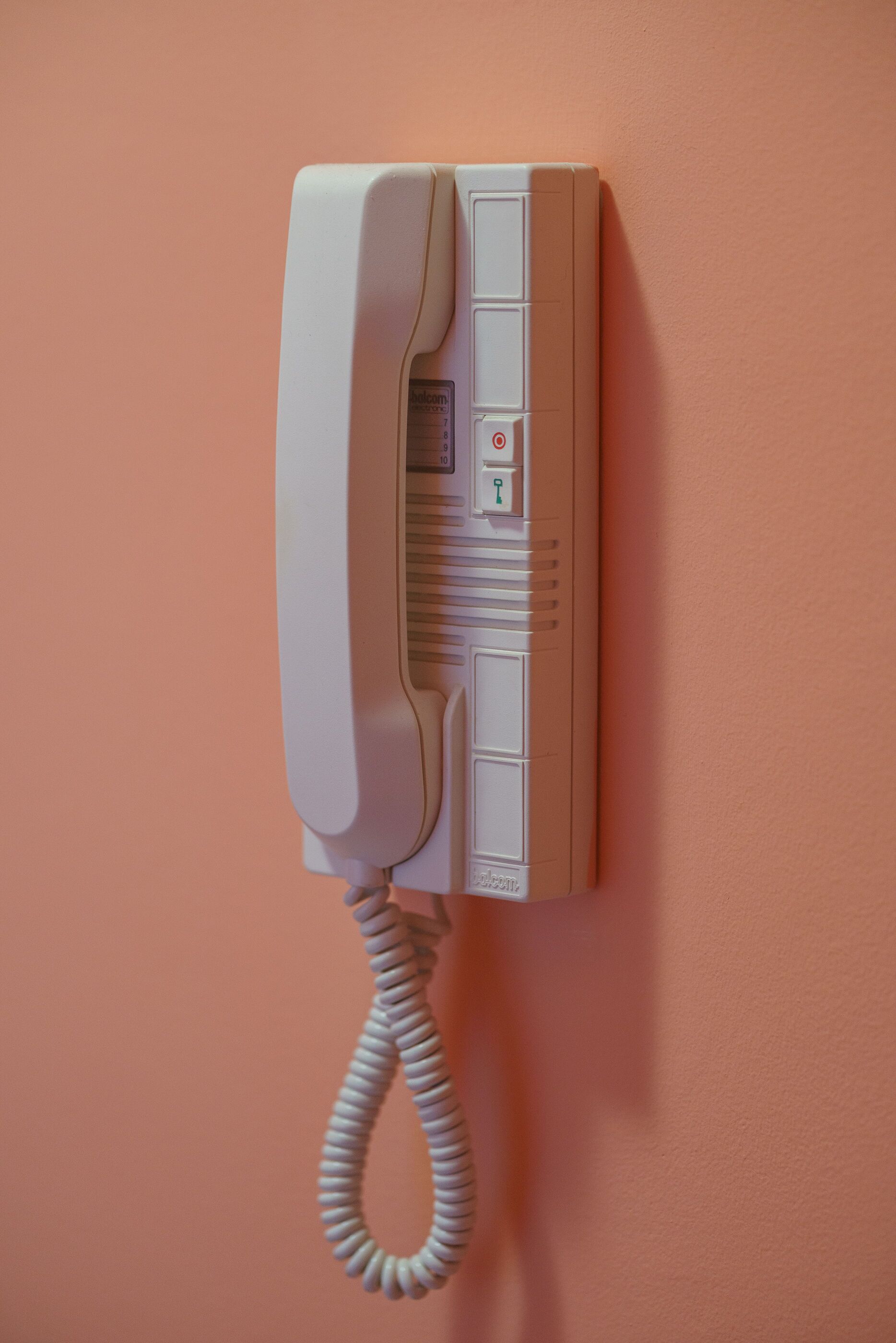 A wall-mounted telephone with a cord.