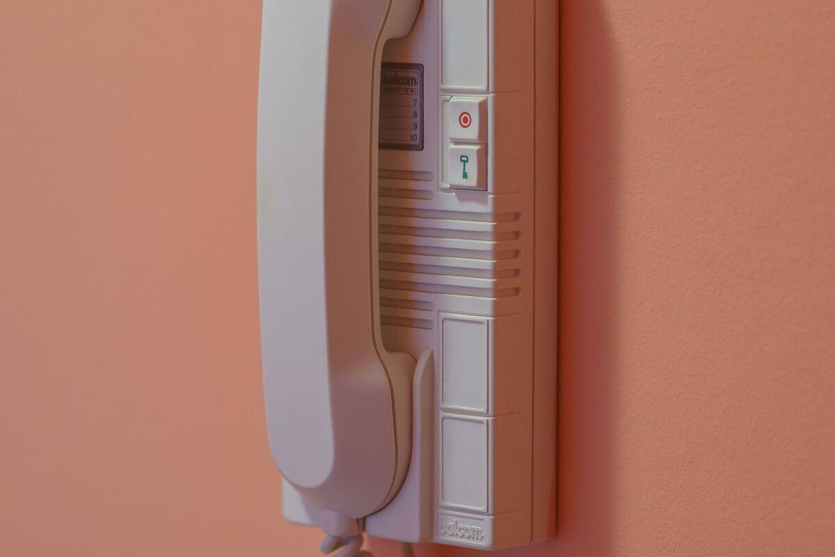 Un téléphone fixé au mur, muni d’un fil.
