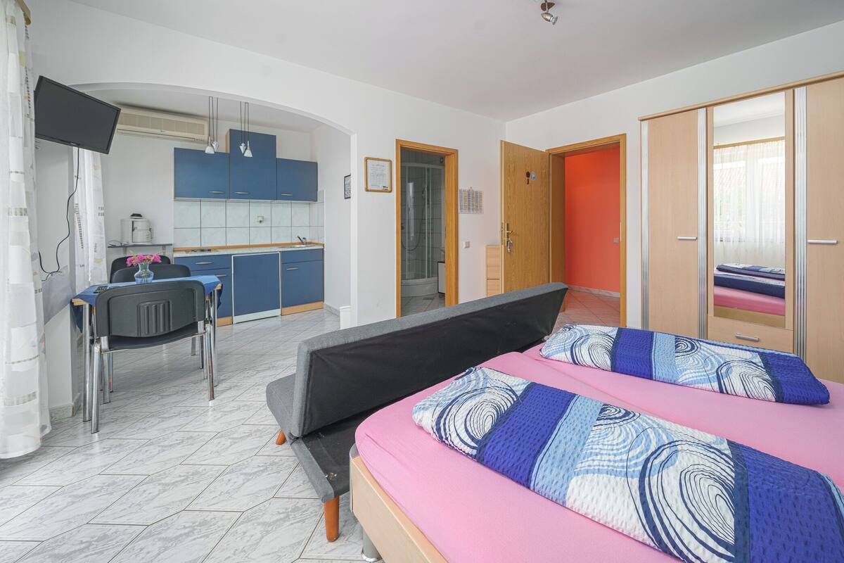 Une chambre avec un lit, un bureau et un coin cuisine.