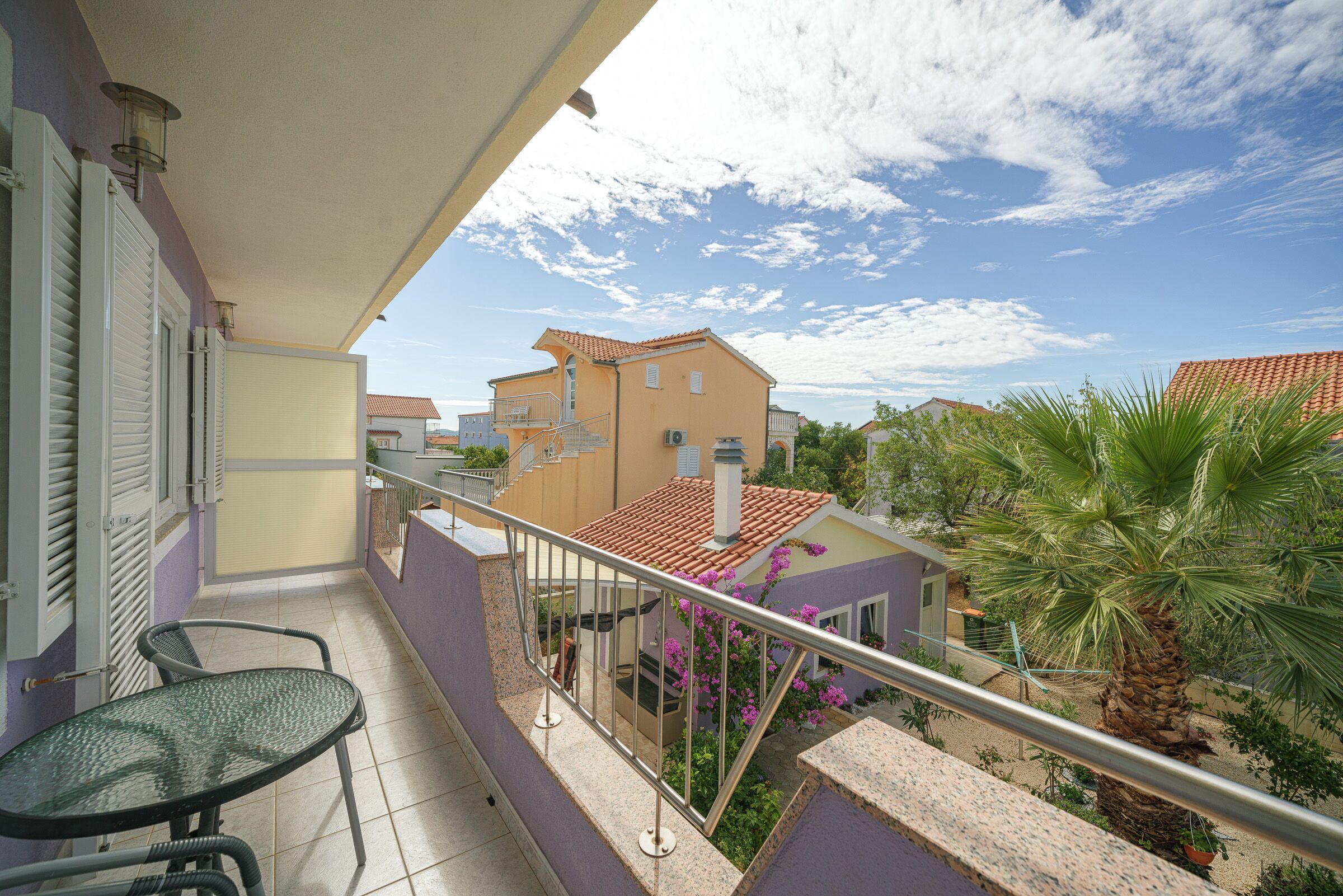 A balcony with a glass railing, a table, and chairs.