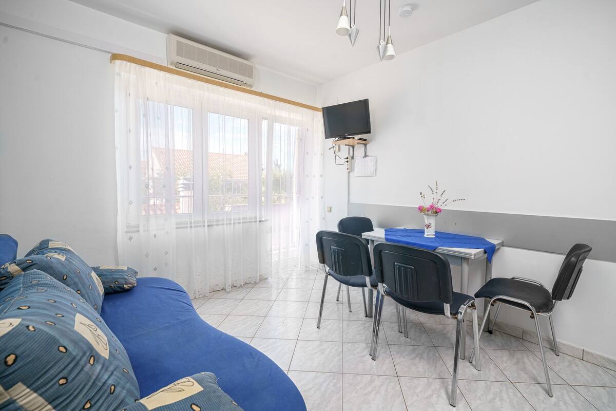 Une chambre d’hôtel avec un lit, un bureau avec des chaises, une télévision et une fenêtre avec des rideaux.