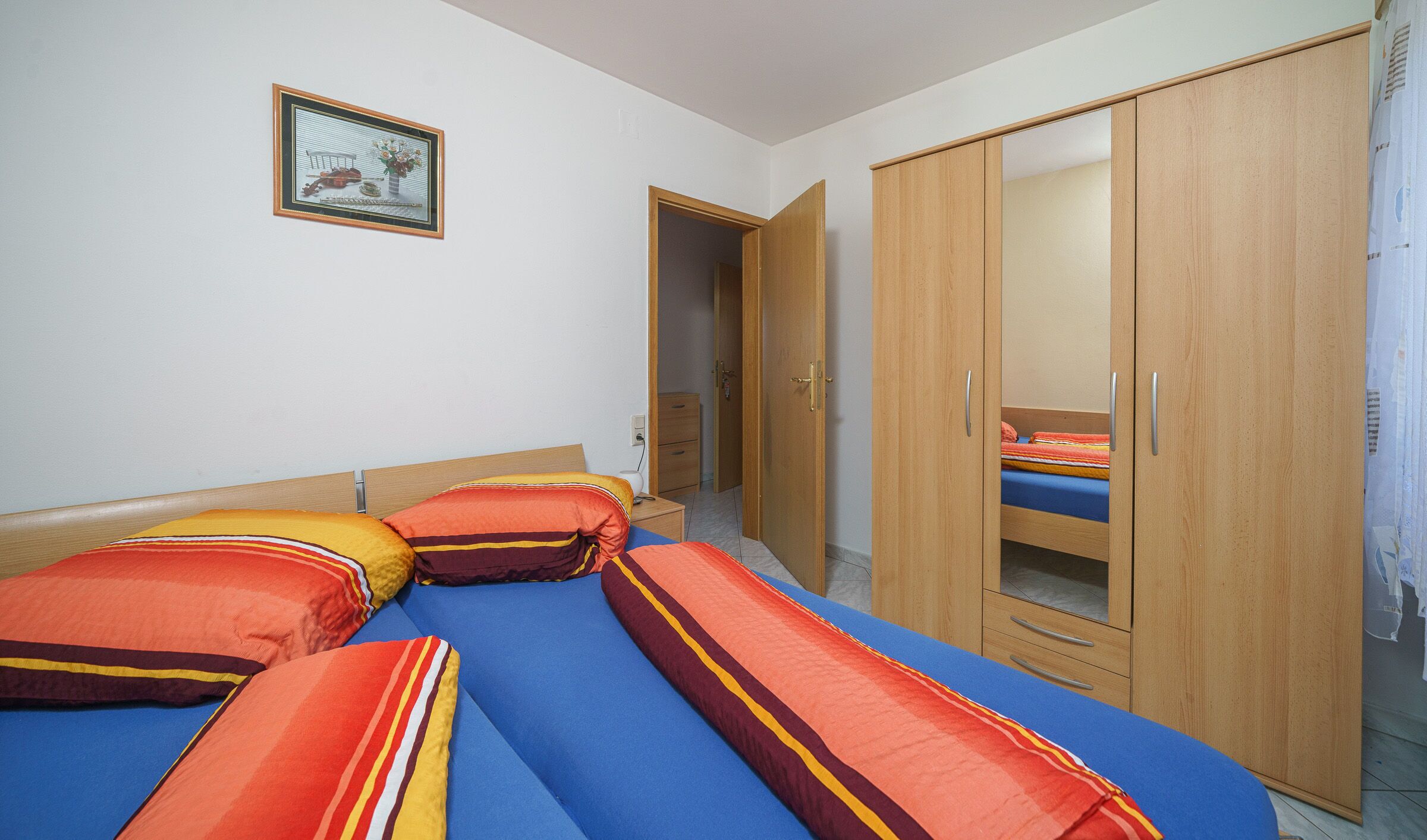A bedroom with a bed, a wardrobe, and a small bedside table.