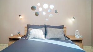 A bedroom with a bed, two bedside tables, a wall-mounted light fixture, and a ceiling with wooden beams. - Apartments Kruno (Zaton)