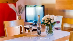 A dining table with a bottle, two wine glasses, and a vase of flowers. - Apartments Kruno (Zaton)