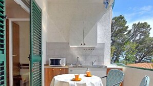 Un balcon avec une table et des chaises, un four à micro-ondes et un coin cuisine.