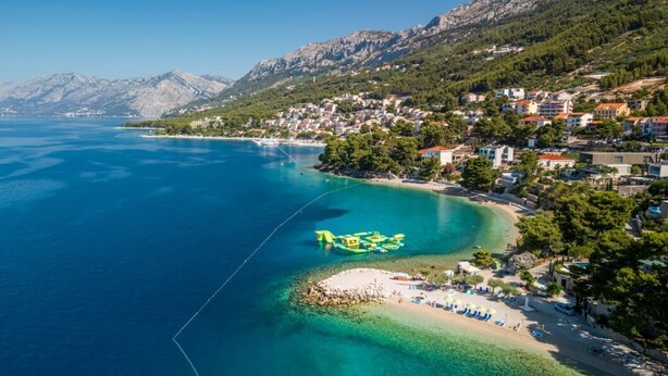 Une ville côtière dotée d’une plage, d’eaux cristallines et bordée de montagnes.