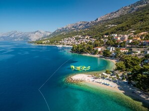 Eine Küstenstadt mit Strand, klarem Wasser und einem Bergpanorama.