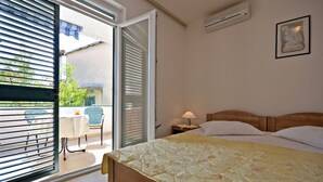 Une chambre à coucher avec un lit, une table de chevet, une lampe et une fenêtre avec des stores.