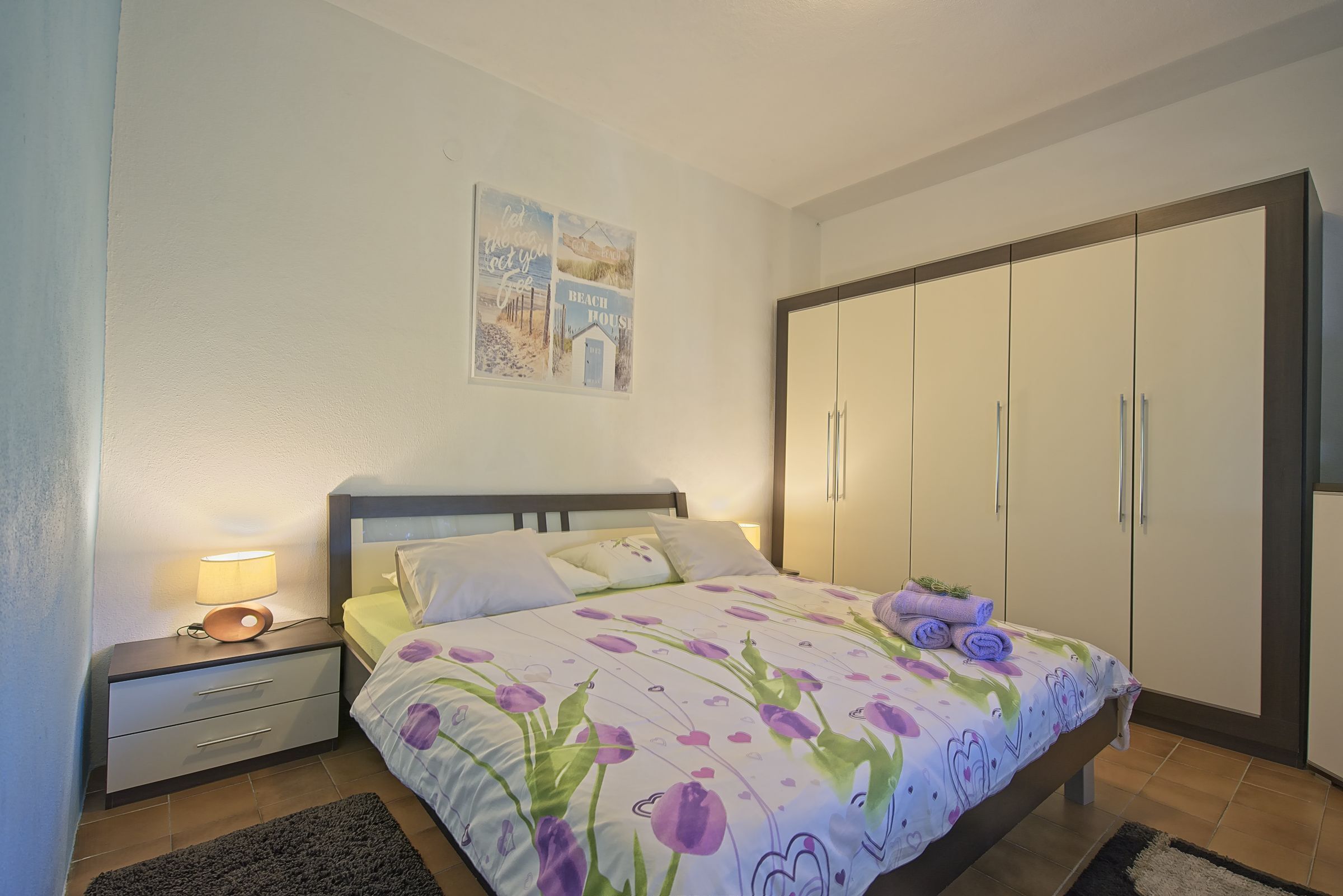 A bedroom with a bed, nightstand, and wardrobe.