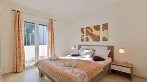 Une chambre à coucher avec un lit, une table de chevet, une fenêtre avec des rideaux et des œuvres d’art accrochées au mur.