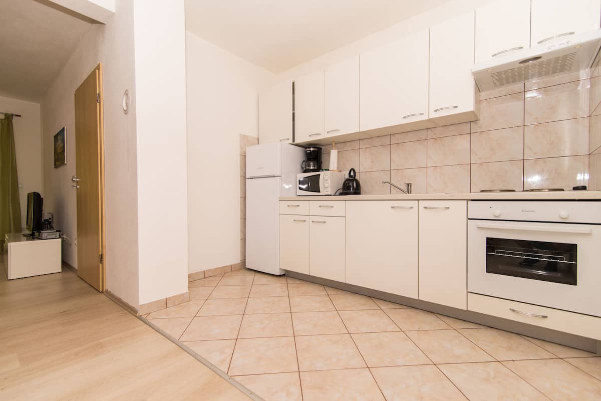 A modern kitchen with white cabinets, a built-in oven, and a microwave.