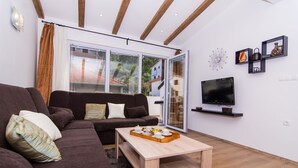 Un salon moderne avec un canapé marron, une table basse en bois avec un plateau, un téléviseur à écran plat et une grande fenêtre avec des rideaux.