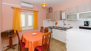 A compact kitchen with a dining area, featuring a table with chairs, a small refrigerator, and a microwave. - Apartment Town View (Korcula)