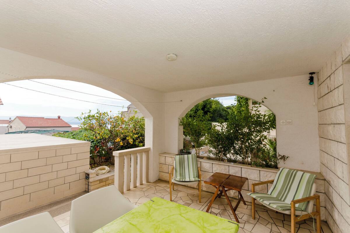 A covered outdoor area with a brick wall, a table, two chairs, and a bench.