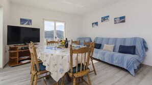 A living room with a TV, dining table, and sofa. - Apartments Bilo (Marina)